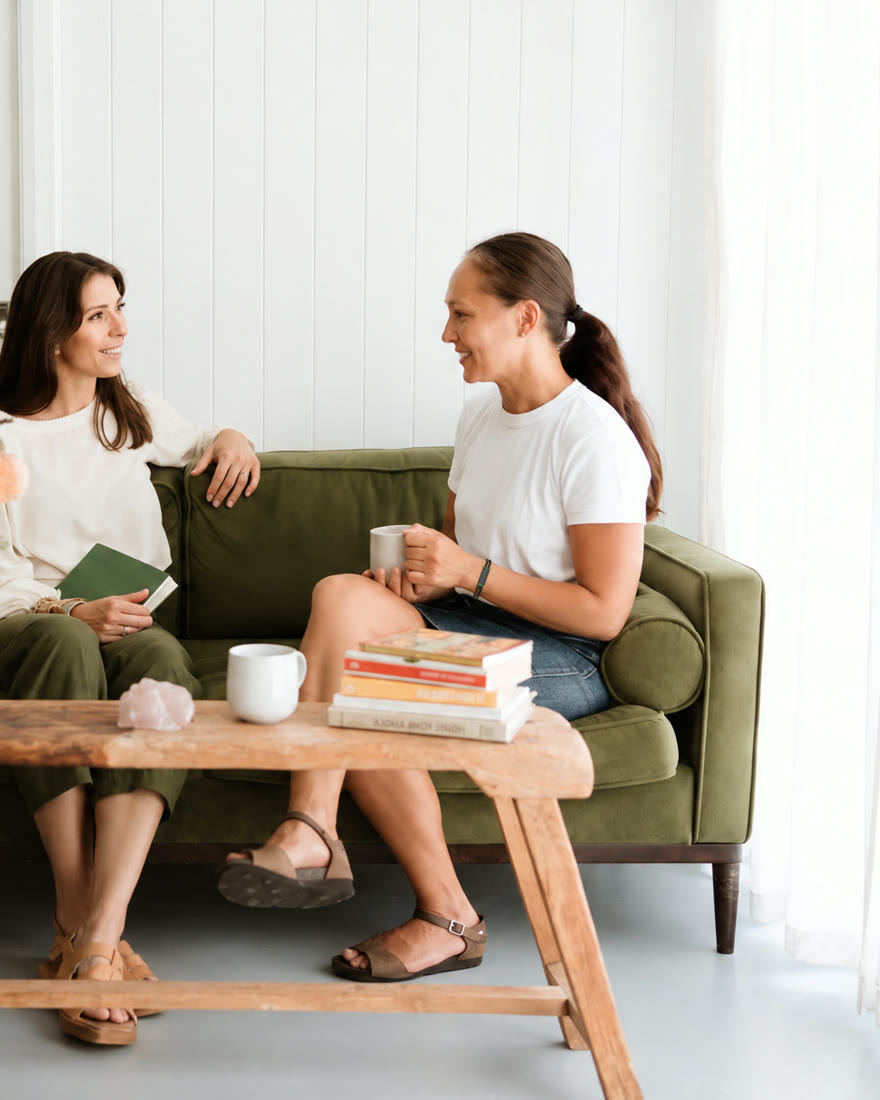 Two women talking on a green sofa over coffee