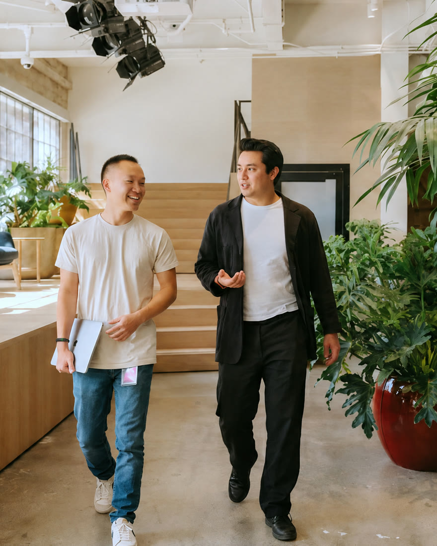Two colleagues walking and talking through a bright office